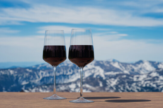 Two glasses of red wine against mountain background. View of snowy peaks in the mountains.