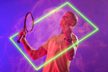 Caucasian tennis player screaming and holding racket by illuminated rectangle on purple background