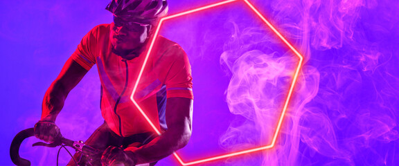 African american male cyclist riding bicycle with illuminated hexagon against purple background