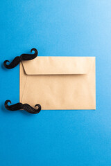 Composition of fake moustaches and envelope on blue background with copy space