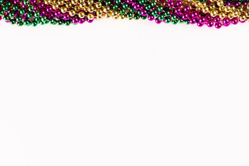 Composition of colourful mardi gras beads with copy space on white background with copy space - obrazy, fototapety, plakaty