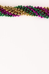 Composition of colourful mardi gras beads with copy space on white background with copy space