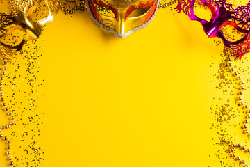 Composition of colourful mardi gras beads and carnival masks on yellow background with copy space - obrazy, fototapety, plakaty