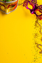 Composition of colourful mardi gras beads and carnival masks on yellow background with copy space - obrazy, fototapety, plakaty
