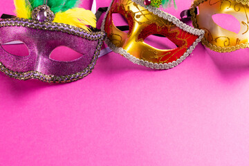 Composition of colourful mardi gras carnival masks on pink background with copy space