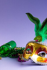 Composition of colourful mardi gras beads, shot glass and carnival mask, on blue with copy space © vectorfusionart
