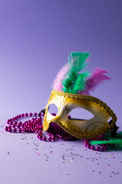 Composition of colourful mardi gras beads and carnival mask on blue background with copy space