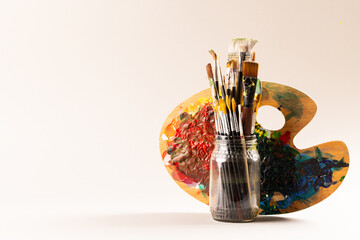 Obraz premium Composition of jar of painting brushes and palette on white background with copy space