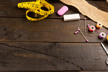 Composition of sewing equipment on wooden background with copy space