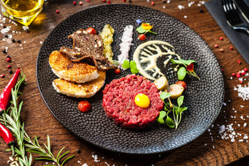 Beef tartare from Black Angus. Onion, quail egg, tomato sauce, mustard mayonnaise. Delicious healthy Italian traditional food closeup served for lunch in modern gourmet cuisine restaurant