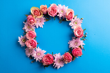 Fototapeta premium Composition of rose wreath on blue background