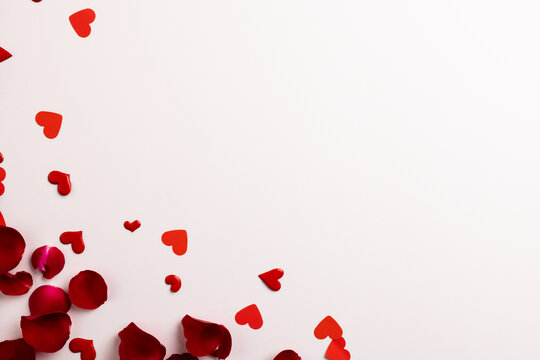 Composition of rose petals and hearts on white background