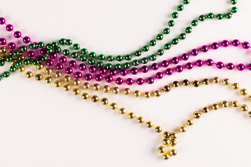 Composition of colourful mardi gras beads on white background with copy space - obrazy, fototapety, plakaty