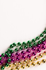 Composition of colourful mardi gras beads on white background with copy space © vectorfusionart