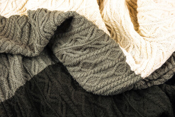 Knitted green and beige background. Close-up of a knitted blanket. Wavy folds material. Knitted warm green and beige sweater or coat.