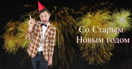 Happy young caucasian man wearing party hat enjoying russian orthodox new year against fireworks