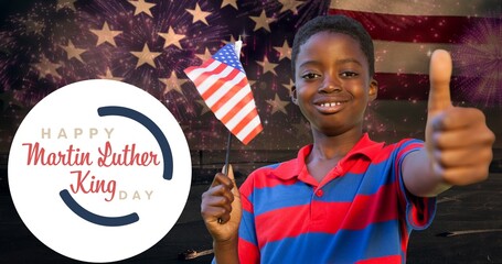 Smiling african american boy holding usa flag showing thumbs up by martin luther king jr day