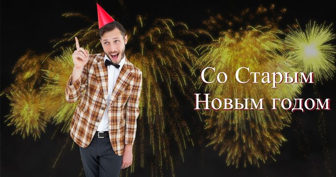 Happy young caucasian man wearing party hat enjoying russian orthodox new year against fireworks