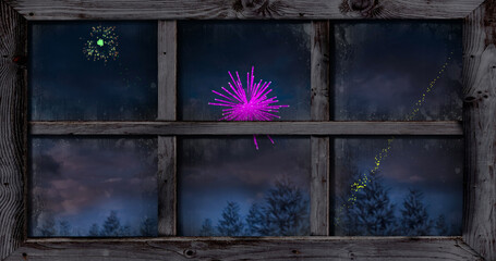 Image of window with colourful christmas and new year fireworks over trees in night sky