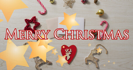 Merry christmas text banner and star icons against christmas decorative items on wooden surface