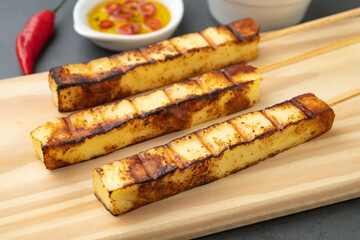 Grilled Rennet or Coalho cheese on a wooden board with sugar syrup and pepper