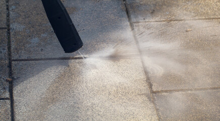 Power cleaning dirty floor, paving slabs with high pressure water jet. Dirt coming out of cracks....