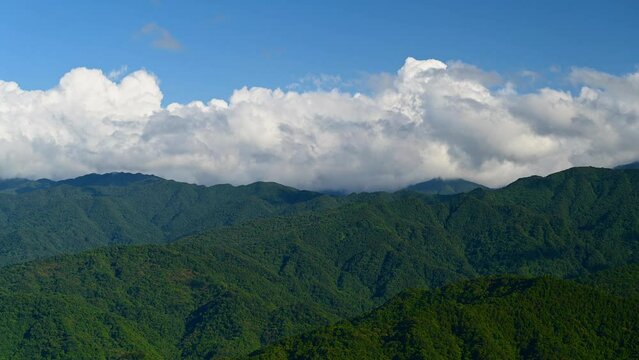 Dramatic white cloud movement in the blue sky. Full of freedom and energy. Blue sky, white clouds and green mountain tops. New Taipei City, Taiwan