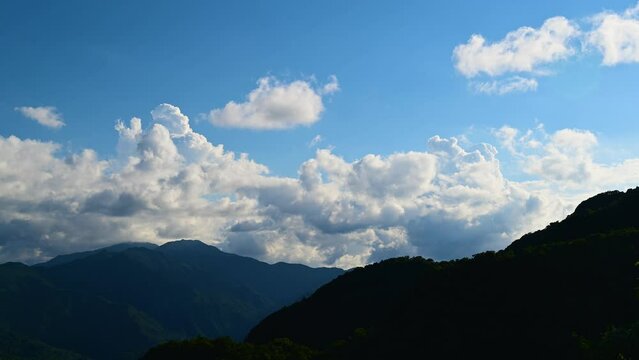 Dramatic white cloud movement in the blue sky. Full of freedom and energy. Blue sky, white clouds and green mountain tops. New Taipei City, Taiwan