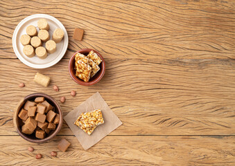 Typical brazilian candies over wooden table. Doce de leite or dulce de leche, pe de moleque and pacoca with copy space