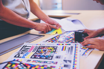 Crop image of worker checking print quality of media graphics proof print in printing industry....