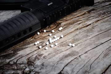 BB gun or airsoft gun muzzle and white bullets on wooden plank, soft and selective focus.