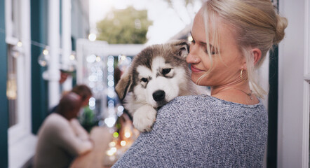 Woman holding her dog with love, care and happiness at a dinner, party or celebration at a house. Happy, smile and lady hugging her husky pet at a festive, new year or christmas event at home. © Kobus L/peopleimages.com