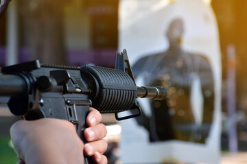 Airsoft Gun or BB Gun holding in hands of shooter while aiming to the destination target at the bb gun or airsoft gun training camp, soft and selective focus, concept for freetimes and outdoor hobby.