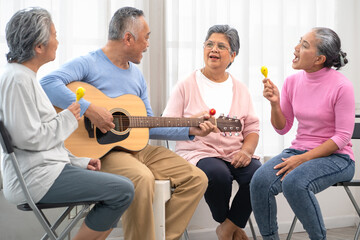 Selective focus senior man happy playing acoustic guitar with friends. Elderly male musician...