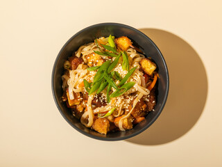 Top view of noodles in a black bowl isolated on beige background.