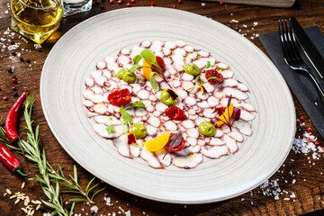 Octopus carpaccio. Spinach cream, cherry tomatoes. Delicious healthy Italian traditional food closeup served for lunch in modern gourmet cuisine restaurant