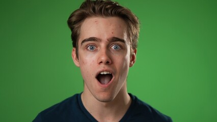 Closeup excited jubilant overjoyed young man 20s doing winner gesture celebrate clenching fists say yes isolated on green screen background studio portrait