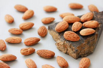 small grains of natural brown almonds on a marble stone on a gray background
