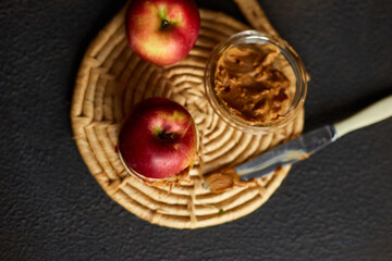 Red slices sandwich or burger of apple with peanut butter on dark background, healthy snack, nutrition and diet food.