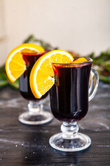 Glass of delicious glintwein or mulled hot wine, cinnamon, thread on vintage wooden background.
