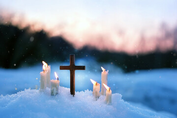 Christian cross and candles on snow, evening winter natural blurred background. Advent time,...