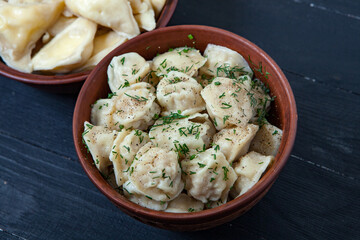 Traditional russian pelmeni or ravioli, dumplings with meat on wood black background. Russian food and russian kitchen concept.