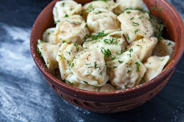 Traditional russian pelmeni or ravioli, dumplings with meat on wood black background. Russian food and russian kitchen concept.