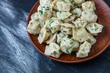 Traditional russian pelmeni or ravioli, dumplings with meat on wood black background. Russian food and russian kitchen concept.