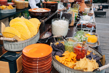 Tavolo per buffet, con tipici cibi messicani. Salse servite in bicchierini di vetro, piatti assortiti.