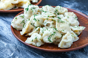Traditional russian pelmeni or ravioli, dumplings with meat on wood black background. Russian food and russian kitchen concept.