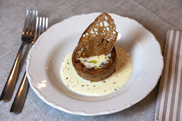 Tortino con cialda di pane, crema bianca di formaggio. Piatto servito su tavola con forchetta in risotrante
