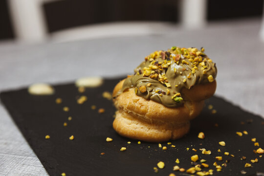 Bignet su piatto di ardesia nera, glassa e granella di pistacchio