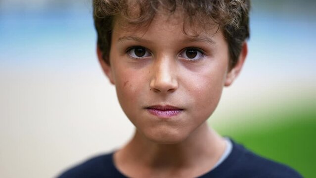 Upset male child looking at camera portrait with serious expression. One little preteen boy feeling anger