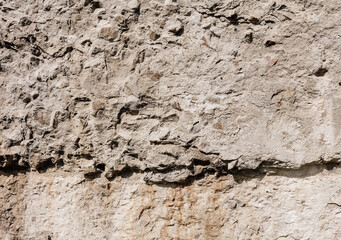 Weathered old wall. Grunge background texture. Plastered stone surface with damages.